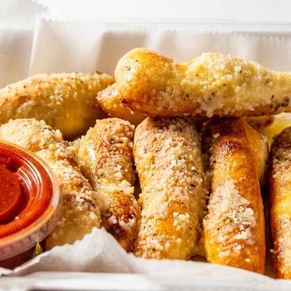 Garlic breadsticks with Parmesan cheese and herbs, served with a side of marinara sauce.