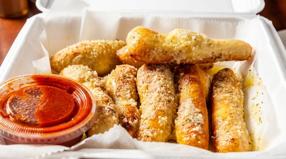 Garlic breadsticks with Parmesan cheese and herbs, served with a side of marinara sauce.
